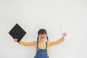 kinderen meisje vervelend een afstuderen pet over- wit achtergrond heel gelukkig en opgewonden aan het doen winnaar gebaar met armen opgevoed, glimlachen en schreeuwen voor succes. viering concept. foto