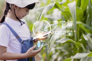 de weinig meisje toepassingen een tablet naar analyseren de groei van planten in de agrarisch verhaal en zichtbaar icoon., de agrarisch technologie concept. slim landbouw aan het leren concept foto