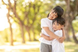 twee Aziatisch weinig kind meisjes knuffelen elk andere met liefde in de tuin ik foto