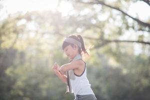 gelukkig kind meisje rennen in de park in zomer in natuur. warm zonlicht gloed. Aziatisch weinig is rennen in een park. buitenshuis sport- en fitheid, oefening en wedstrijd aan het leren voor kind ontwikkeling. foto