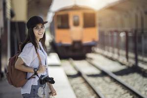 reiziger vrouw wandelen en wacht trein Aan spoorweg platform foto