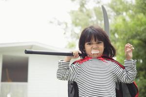 kinderen meisje vervelend mysterieus halloween jurk Holding een sikkel Aan wit achtergrond foto