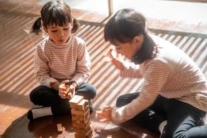 twee Aziatisch meisjes spelen houten stapels Bij huis foto