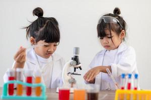 opleiding, wetenschap, chemie en kinderen concept - kinderen of studenten met test buis maken experiment Bij school- laboratorium foto