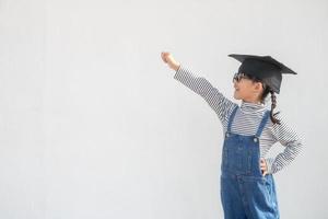 kinderen meisje vervelend een afstuderen pet over- wit achtergrond heel gelukkig en opgewonden aan het doen winnaar gebaar met armen opgevoed, glimlachen en schreeuwen voor succes. viering concept. foto