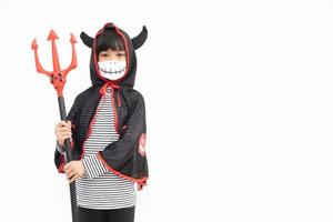 Aziatisch weinig meisje in een halloween kostuum in een medisch masker . halloween met veiligheid maatregelen van covid-19 foto