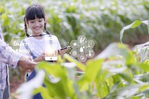 de weinig meisje toepassingen een tablet naar analyseren de groei van planten in de agrarisch verhaal en zichtbaar icoon., de agrarisch technologie concept. slim landbouw aan het leren concept foto