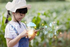 de weinig meisje toepassingen een tablet naar analyseren de groei van planten in de agrarisch verhaal en zichtbaar icoon., de agrarisch technologie concept. slim landbouw aan het leren concept foto