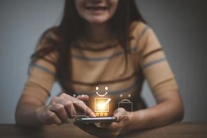 klant tevredenheid concept. vrouw hand- Holding smartphone tonen beoordeling met vijf sterren goud symbool en smiley gezicht voor haar tevredenheid. foto