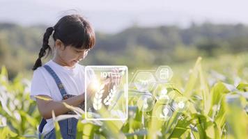 de weinig meisje toepassingen een tablet naar analyseren de groei van planten in de agrarisch verhaal en zichtbaar icoon., de agrarisch technologie concept. slim landbouw aan het leren concept foto