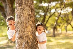 weinig meisje is spelen verstoppertje schuilplaats gezicht in de park foto