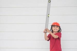 Aziatisch meisje kinderen spelen net zo een ingenieur helm foto