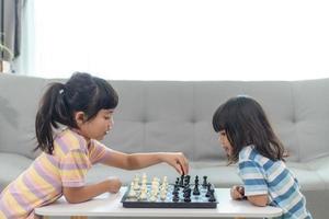 weinig broer of zus meisje spelen schaak Bij huis. foto