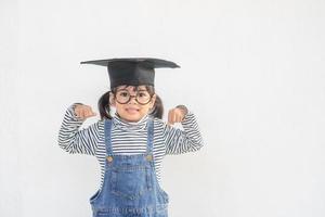 kinderen meisje vervelend een afstuderen pet over- wit achtergrond heel gelukkig en opgewonden aan het doen winnaar gebaar met armen opgevoed, glimlachen en schreeuwen voor succes. viering concept. foto