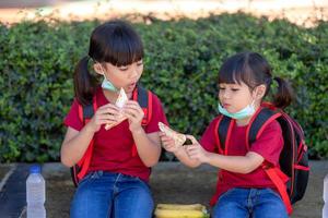 kinderen aan het eten buitenshuis Bij de school. gezond school- ontbijt voor kinderen. belegd broodje tijd. foto