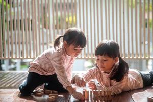 twee Aziatisch meisjes spelen houten stapels Bij huis foto