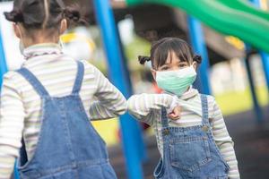 nieuw normaal levensstijl, sociaal afstand nemen concept. gelukkig kinderen vervelend gezicht maskers hebben pret Aan Bij speelplaats beschermen coronavirus covid19, foto