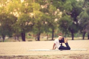 weinig schattig Aziatisch meisje beoefenen yoga houding Aan een mat in park, gezond en oefening concept foto