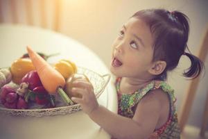 klein meisje spelen met groenten foto