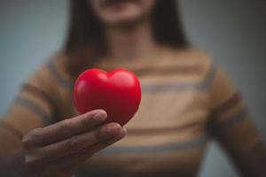 vrouw handen Holding rood hart, wereld mentaal Gezondheid dag en wereld hart dag, leven en Gezondheid verzekering, csr sociaal verantwoordelijkheid, foto