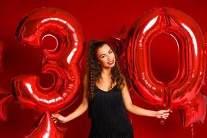 jonge volwassen vrouw op de achtergrond van rode ballonnen foto