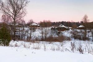 roze winter zonsondergang onder rustiek huizen foto