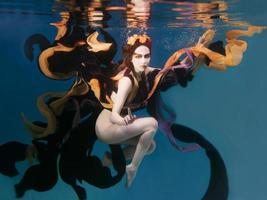 mooi artistiek jong vrouw in jurk dansen onderwater. meermin, oogst, dans, fee concept foto