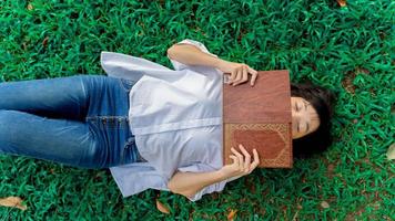 jong vrouw aan het liegen Aan de gras en kom tot rust van lezing boek foto