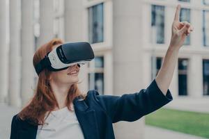 gelukkige jonge zakenvrouw die een virtual reality-bril gebruikt terwijl ze buiten staat foto