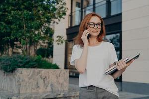 nadenkende roodharige vrouw kijkt in de verte maakt telefoontje houdt smartphone bij oor foto