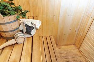 interieur details Finse sauna stoomkamer met traditionele sauna accessoires wastafel berken bezem scoop vilten hoed handdoek. traditioneel oud russisch badhuis spa concept. ontspannen land dorp bad concept. foto