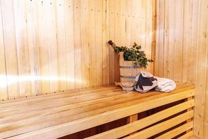 interieur details Finse sauna stoomkamer met traditionele sauna accessoires wastafel berken bezem scoop vilten hoed handdoek. traditioneel oud russisch badhuis spa concept. ontspannen land dorp bad concept. foto