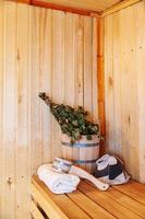 interieur details Finse sauna stoomkamer met traditionele sauna accessoires wastafel berken bezem scoop vilten hoed handdoek. traditioneel oud russisch badhuis spa concept. ontspannen land dorp bad concept. foto