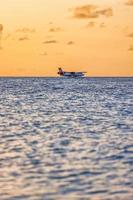 02.02.22, ari atol exotisch tafereel watervliegtuig Aan Maldiven zee landen. watervliegtuig landen Aan zonsondergang zee. vakantie of vakantie in Maldiven achtergrond. lucht vervoer, landen watervliegtuig Aan de dageraad kust foto