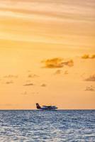 02.02.22, ari atol exotisch tafereel watervliegtuig Aan Maldiven zee landen. watervliegtuig landen Aan zonsondergang zee. vakantie of vakantie in Maldiven achtergrond. lucht vervoer, landen watervliegtuig Aan de dageraad kust foto