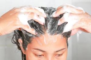 Aziatisch vrouw het wassen haar haar- terwijl nemen een douche. foto