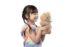 schattig weinig Aziatisch meisje knuffelen haar favoriete bruin teddy beer en glimlachen in wit achtergrond. foto