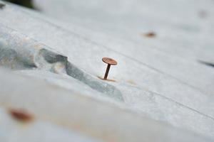 roestig ijzer gaten en nagels Aan een oud gebogen metaal dak. roestig ijzer nagels foto