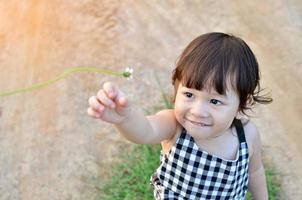 schattig weinig meisje is Bezig met verzenden bloemen in haar hand- naar iemand de avond atmosfeer met zacht zonlicht foto