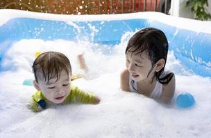 zus en broer hebben pret spelen met bubbels in de zwemmen zwembad Bij huis. zomer water Speel, familie geluk, kinderen geluk foto