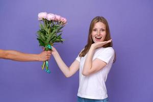 prachtig jong dame is opgewonden naar te ontvangen boeket pioenen voor vrouwen dag foto