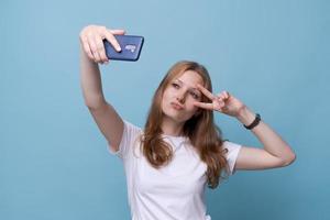 portret gelukkig vriendelijk jong Kaukasisch meisje in wit t-shirt Aan blauw foto