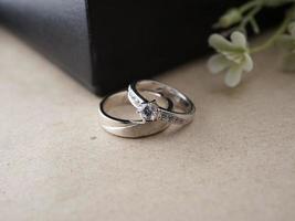 bruiloft ring Aan een houten baseren met een zwart ringdoos achtergrond en kunstmatig bloemen foto