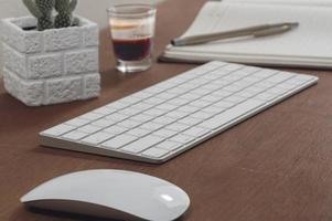 toetsenbord, muis en kamerplant met espresso op houten tafel foto