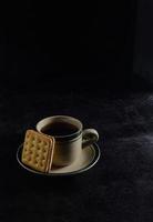 zwart koffie en biscuits Aan de zwart achtergrond foto