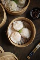 verticaal visie van divers dimsum in bamboe mand Aan de houten tafel foto