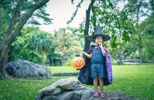 klein meisje in een heksenkostuum met een pompoenlamp foto