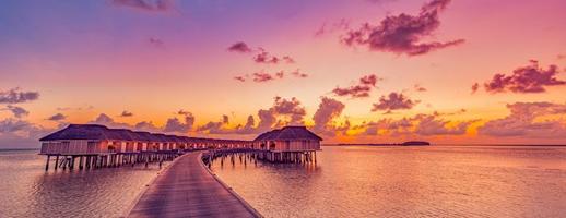 verbazingwekkend tropisch zonsondergang panorama Bij Maldiven eilanden. luxe toevlucht villa's zeegezicht met zacht LED lichten kleurrijk droom lucht. fantastisch zomer vakantie concept, vakantie landschap zonsopkomst zee horizon foto