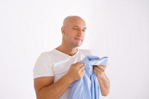 een kaal Mens Holding een schoon overhemd Aan een wit achtergrond foto