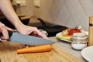 vrouw hakken wortel in keuken, dichtbij omhoog foto